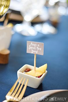 there is a small sign on top of some fruit in a bowl with a fork