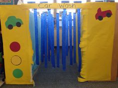 two cardboard cars are sitting in front of a car wash door with blue strips on it