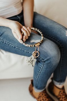 a woman is sitting on a couch with her legs crossed and holding onto a bracelet