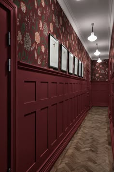 an empty hallway with red walls and floral wallpaper on the walls is lit by recessed lights