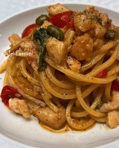 a white plate topped with pasta covered in sauce and chicken meat, garnished with green peppers