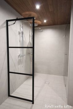 an empty bathroom with a shower and tiled floor in the corner, next to a wooden ceiling