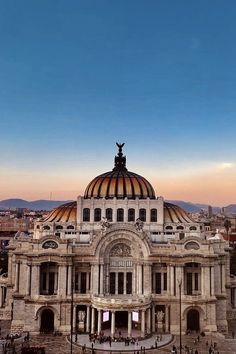 an old building with a dome on top in the middle of a city square at sunset