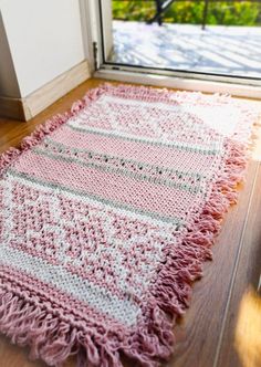 a pink and white rug sitting on top of a wooden floor next to a door