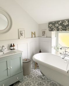 a white bath tub sitting under a bathroom window