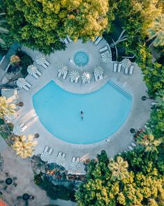 an aerial view of a pool surrounded by trees