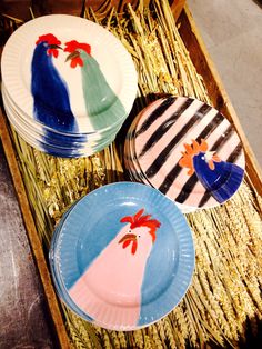 three plates with designs painted on them sitting in a wicker basket next to each other