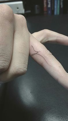 a person's hand with a tiny tattoo on it, holding the finger of another persons hand