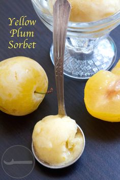 a spoon with some ice cream on it next to two lemons and a glass bowl