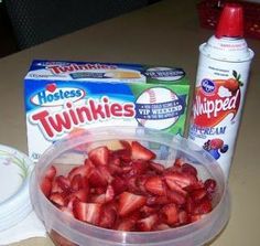 strawberries and yogurt are sitting on a table next to a container of twinkies