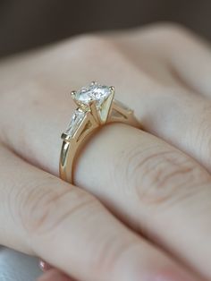 a close up of a person's hand holding a ring with a diamond on it