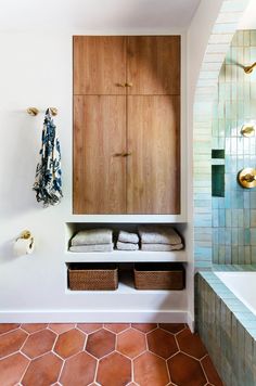 a bathroom with tiled floors and wooden cabinets in the corner, along with baskets on the wall