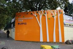 an orange wall with white trees painted on it and a man walking down the street