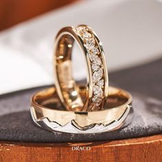 two wedding rings sitting on top of a wooden table next to each other with diamonds in them