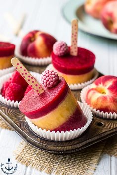 small cupcakes with raspberries on them are sitting on a tray