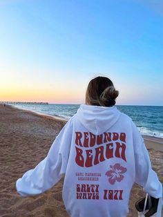 the back of a person wearing a white hoodie at the beach