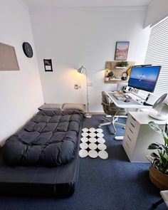 a bed sitting in the middle of a room next to a desk and computer monitor