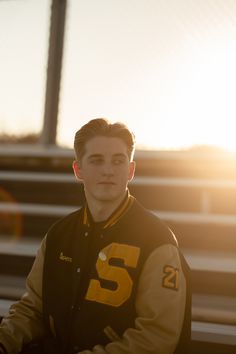 a young man is sitting on the bleachers with his hands in his pockets