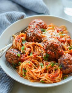 a white bowl filled with spaghetti and meatballs