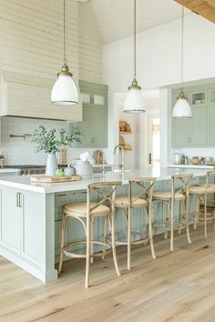 a large kitchen with an island and chairs in front of the counter top, along with two pendant lights