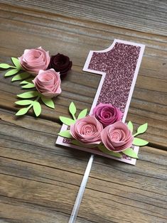 the number one is made out of paper and has pink flowers on top of it