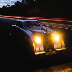 an old car is parked on the side of the road with its headlights turned off