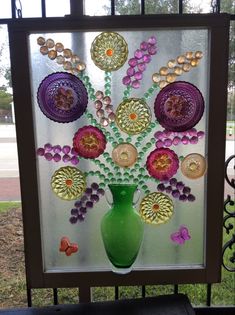 a green vase filled with lots of different colored flowers on top of a window sill