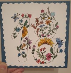 a hand holding up a card with flowers and butterflies on it's front side