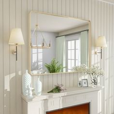 a living room with a fireplace, mirror and vases on the mantel in front of it