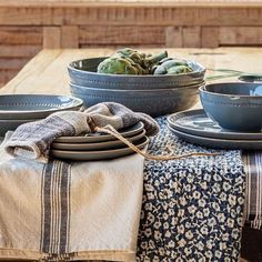 the table is set with plates and bowls on it, along with succulents