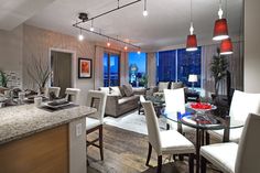 a living room filled with furniture next to a kitchen and dining room table in front of a large window