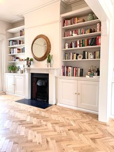 a living room filled with furniture and a fire place under a mirror on top of a wooden floor