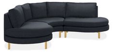 a black sectional couch sitting on top of a white floor next to a wooden leg stool