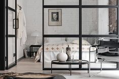 the interior of a modern apartment with white brick walls and black furniture, including a small round dining table