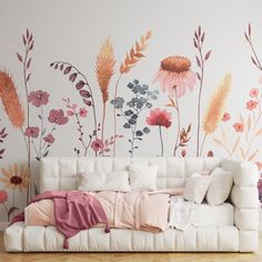 a white couch sitting next to a wall with flowers painted on it