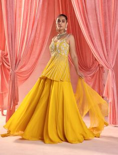 Embrace sophistication with this chic ensemble: an embellished peplum top paired elegantly with a sharara bottom. Complete the look with a dupatta adorned with charming frills, adding a touch of grace and flair to your outfit. Yellow Bollywood Georgette Sharara, Yellow Georgette Bollywood Sharara, Bollywood Style Yellow Georgette Sharara, Yellow Anarkali Floor-length Sharara, Yellow Georgette Gown With Dabka Work, Yellow Anarkali Sharara Floor-length, Yellow Anarkali Style Floor-length Sharara, Yellow Georgette Designer Dresses, Designer Yellow Georgette Dresses