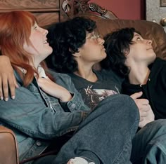 three young women are sitting on a couch and one is kissing the other's cheek