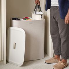 a man standing in front of a trash can holding a pair of scissors and a bag