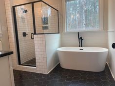 a white bath tub sitting under a window next to a sink