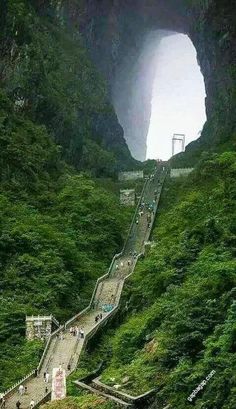 the stairs lead up to an opening in the mountain side with people walking on them