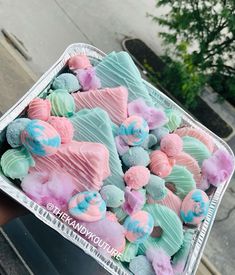 a person holding a tray full of colorfully decorated cookies