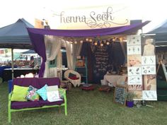 an outdoor tent set up with furniture and decorations on the grass at a flea market