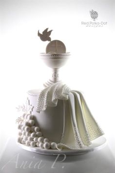 a white cake with pearls and a cross on top is sitting on a plate in front of a white background