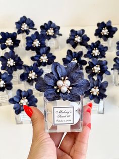 a person holding a small blue flower in front of several smaller flowers with pearls on them