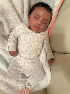 a baby sleeping on top of a white blanket