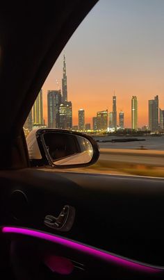 a view from inside a car looking at the city lights and skyscrapers in the distance