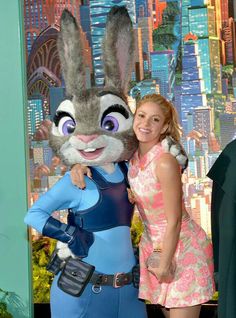 a woman standing next to a rabbit mascot at a movie event in front of a backdrop