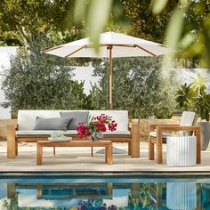 an outdoor patio furniture set next to a pool with flowers on the table and chairs