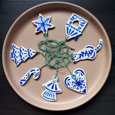 blue and white ceramic ornaments on a plate with green string attached to them, sitting on a wooden table