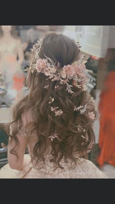 the back of a woman's head with flowers in her hair and long curly hair